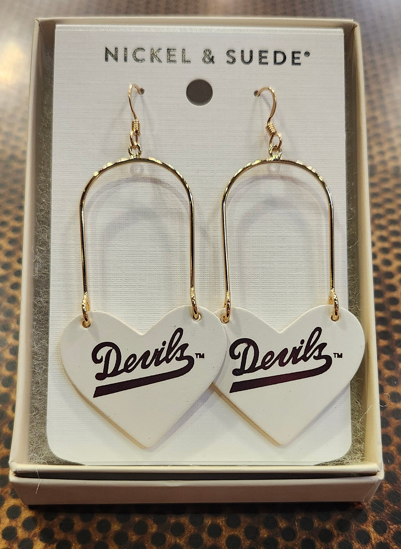 Gold earrings with gold fasteners and cream hearts with 'Devils' in cursive maroon.