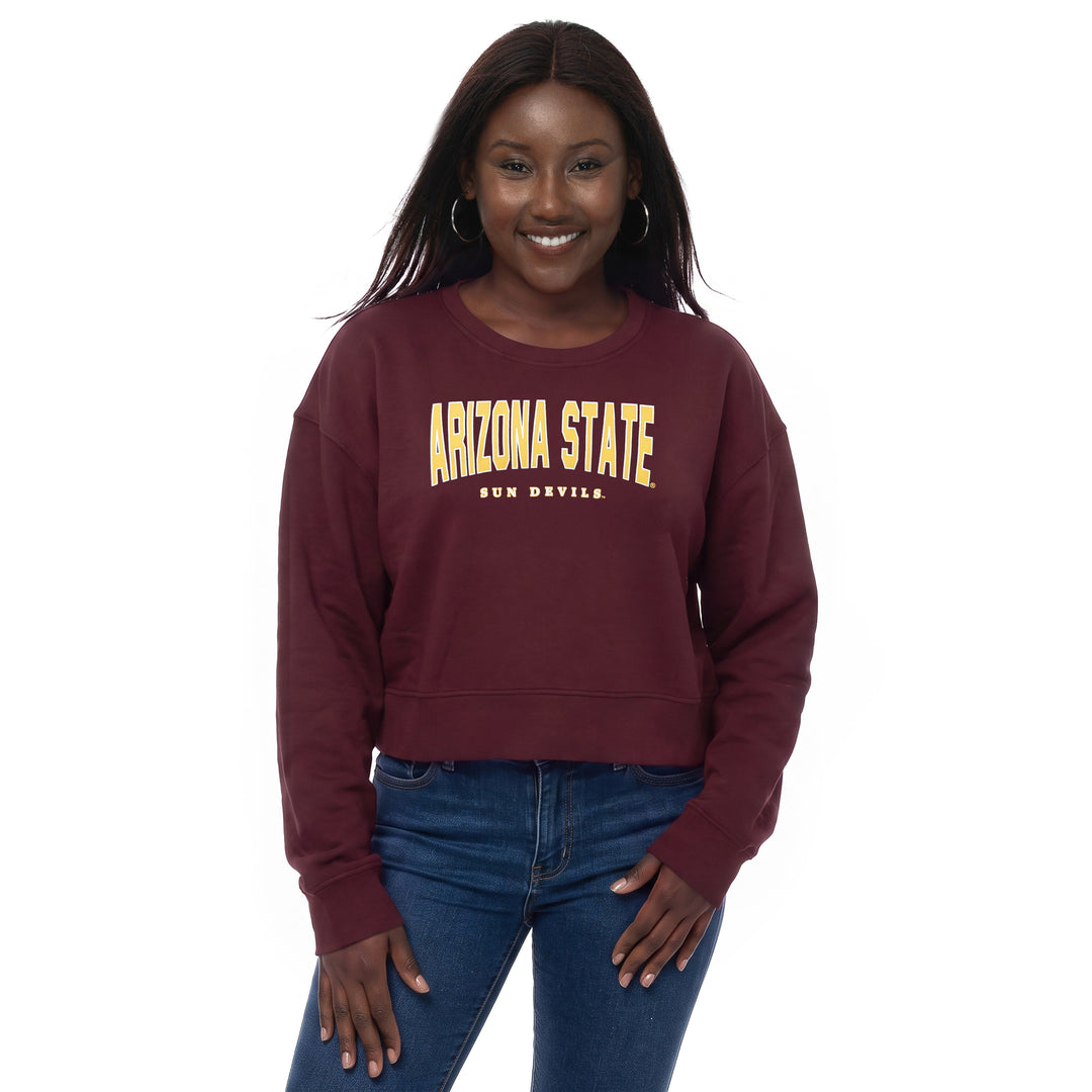 A woman modeling a maroon cropped sweatshirt with &
