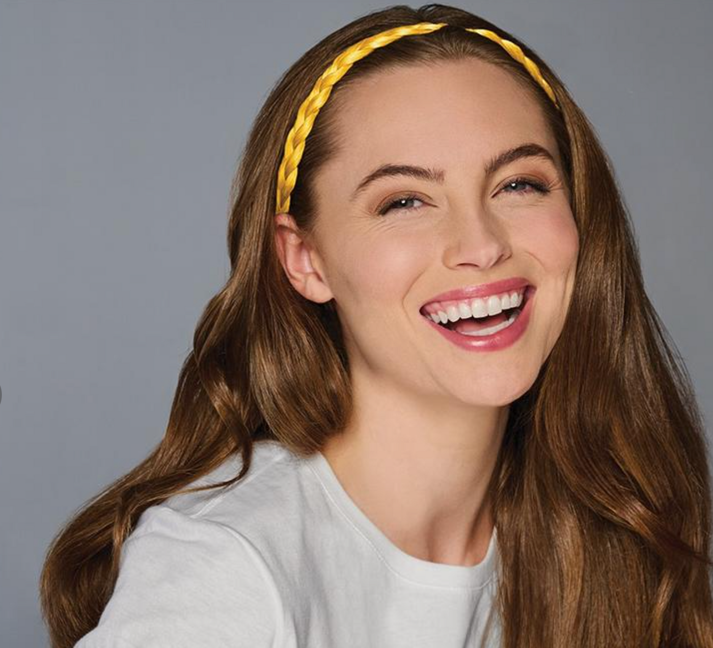 Woman wearing a yellow headband against a gray background