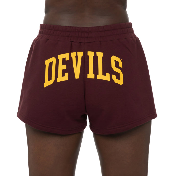 A person wearing maroon sweat shorts with &