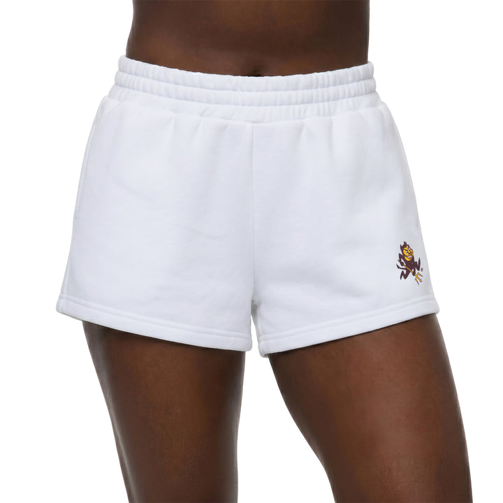 White athletic shorts with an elastic waistband, featuring a small embroidered mascot logo on the lower left leg, shown on a model against a white background.