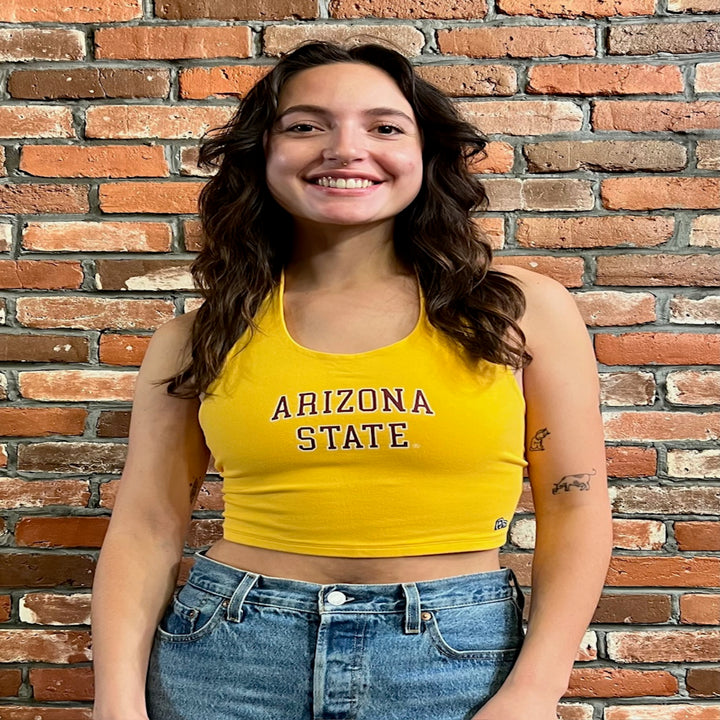 Model wearing cropped halter top in gold. Text reads &