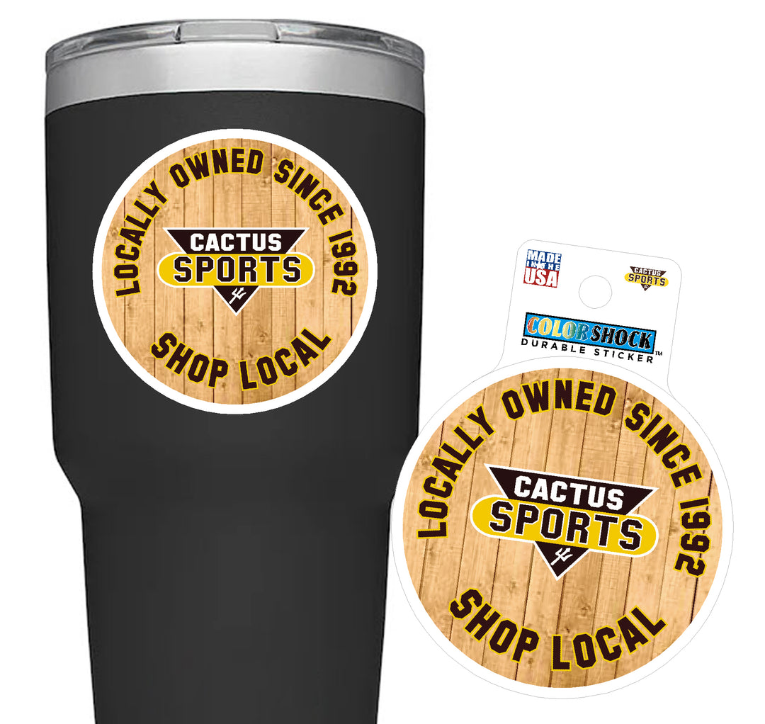 Circular magnet with white outline and wooden background, Cactus Sports logo in the center, "Locally owned since 1992 shop local" around it, displayed on a black tumbler.