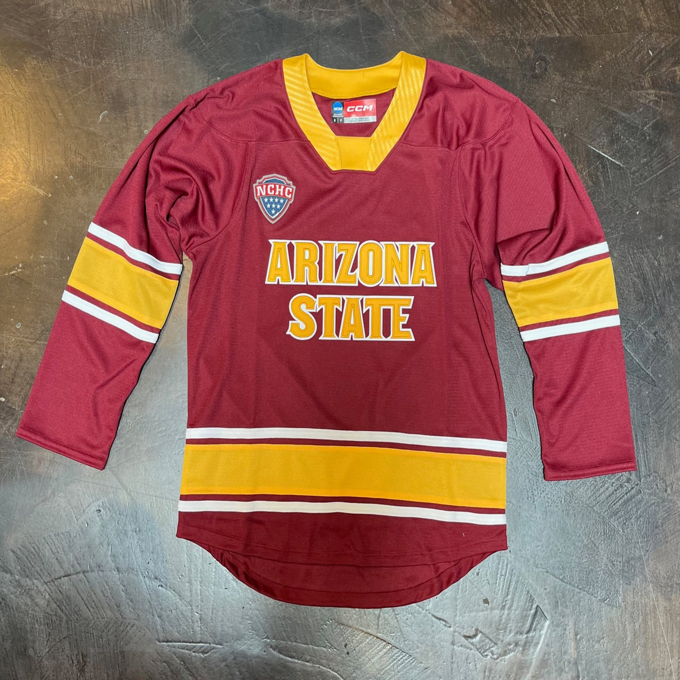 ASU Maroon hockey jersey. There are white and gold blocked of color on the ends of the jersey and the middle of the arms. The collar is outlined in gold. Then 