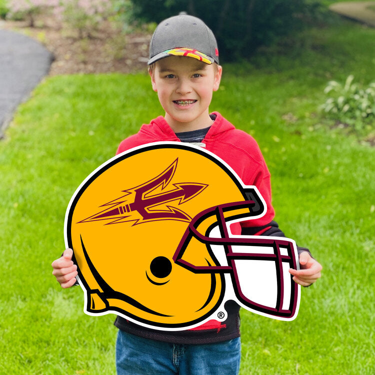 Boy holdijng lawn sign in grass of gold football helmet profile with maroon pitchfork on side