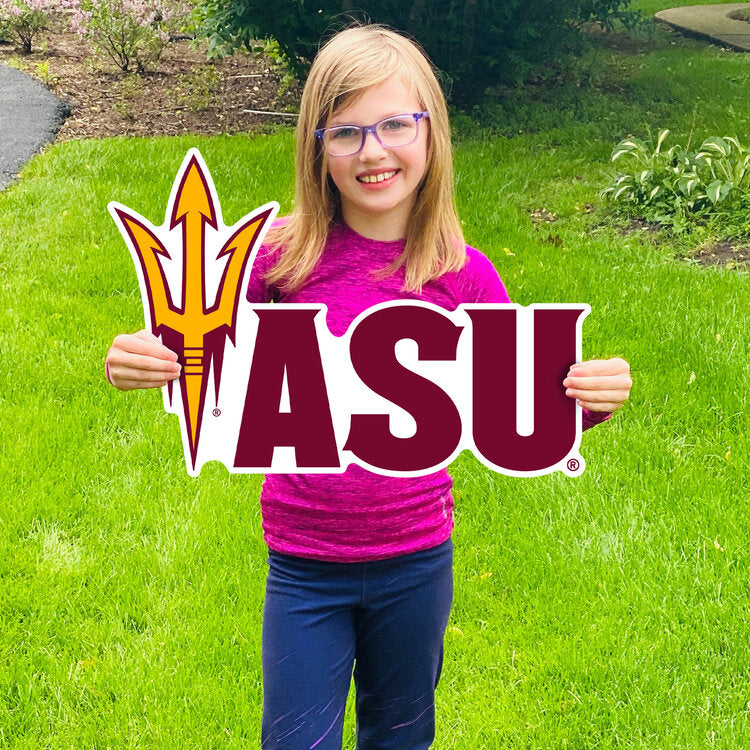 Girl holding lawn sign in grass with pitchfork and 'ASU' lettering