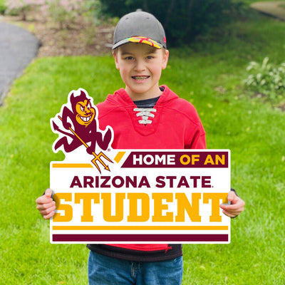 Boy holding ASU lawn sign in grass of Sparky above 'Home of an Arizona State Student' lettering