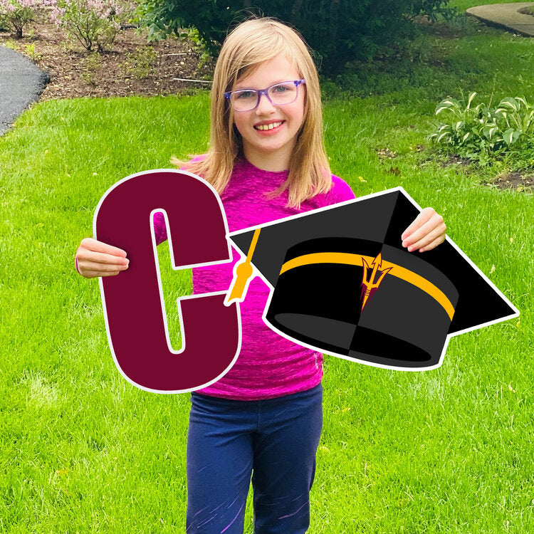 Girl hold 'C' and black ASU graduation cap lawn sign