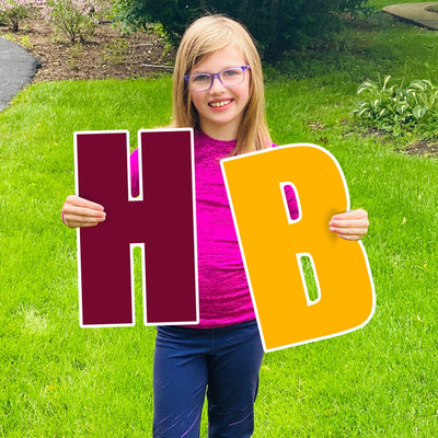Girl holding 'H' and 'B' lawn sign letters