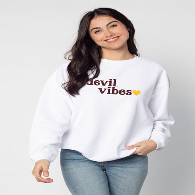 ASU white long sleeve crew. "Devil vibes" text in maroon on the chest of the shirt accompanied by a gold heart. Fabric has a vertical corded texture. 