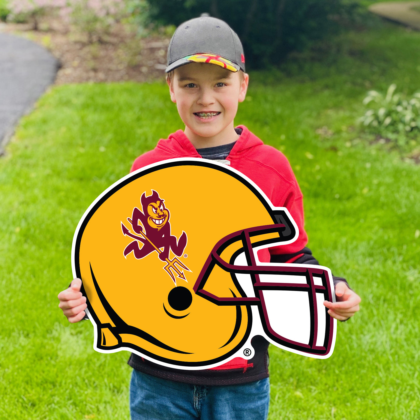 Boy hold ASU lawn sign in grass of gold football helmet with maroon  mask and Sparky on side