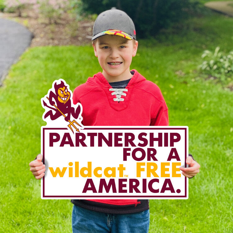 Boy holding ASU lawn sign in grass with Sparky and 'Partnership for a wildcat free America' lettering