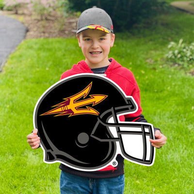 Boy holding a sign on a lawn of ASU football helmet lawn sign in black with gold sideways pitchfork outline across the side 